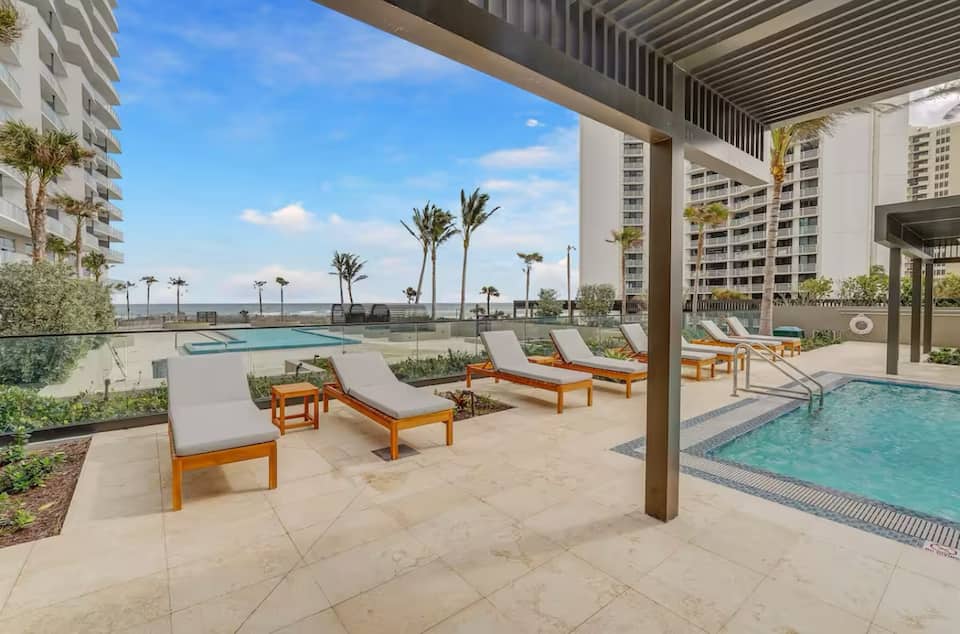 The oceanfront pool deck at the resort, with sun loungers and a shaded cabana