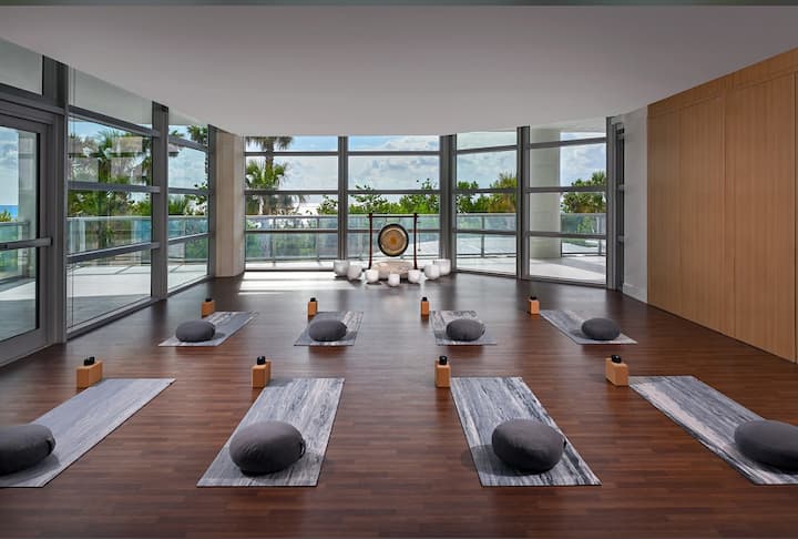 A wellness studio with yoga mats and bolsters on a wood floor