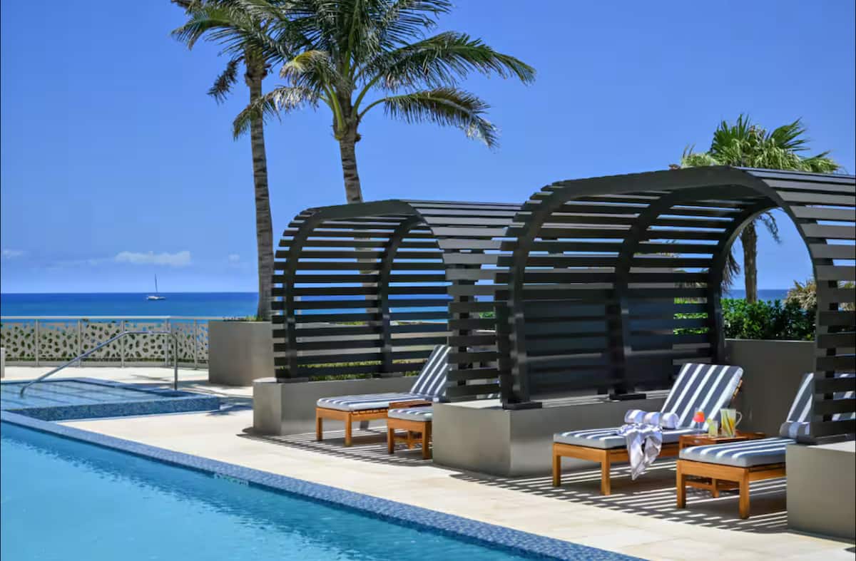 Beach cabanas and loungers among palms beside the pool