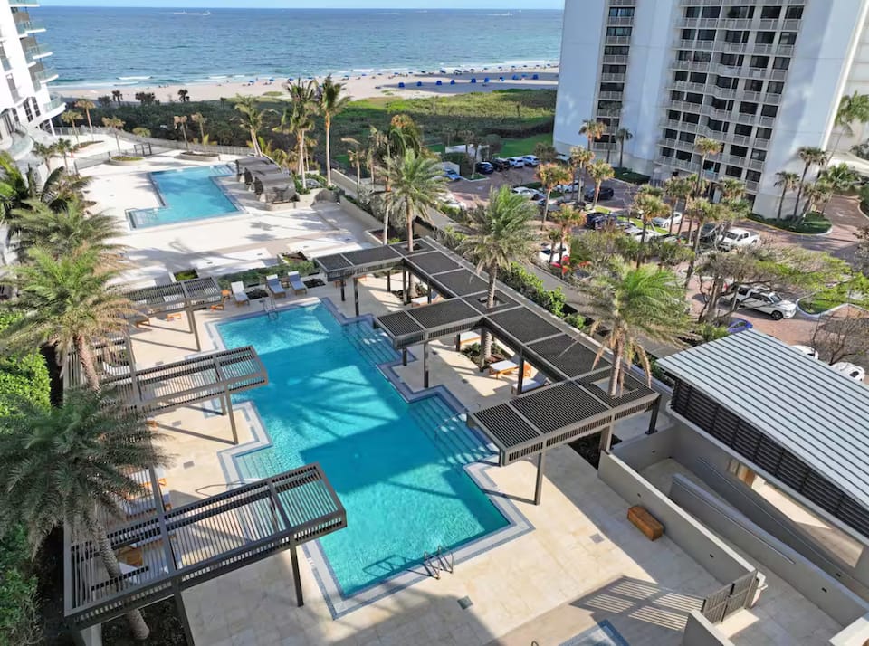 Aerial view of the resort's long lap pool and deck beside the sand