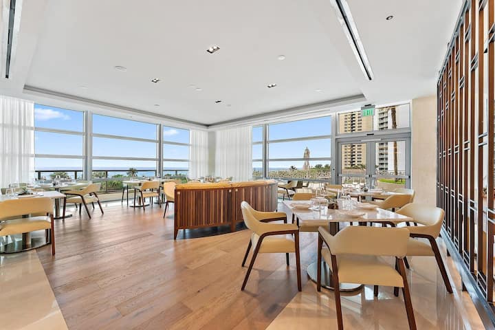 A resort restaurant dining room with ocean views through floor-to-ceiling glass