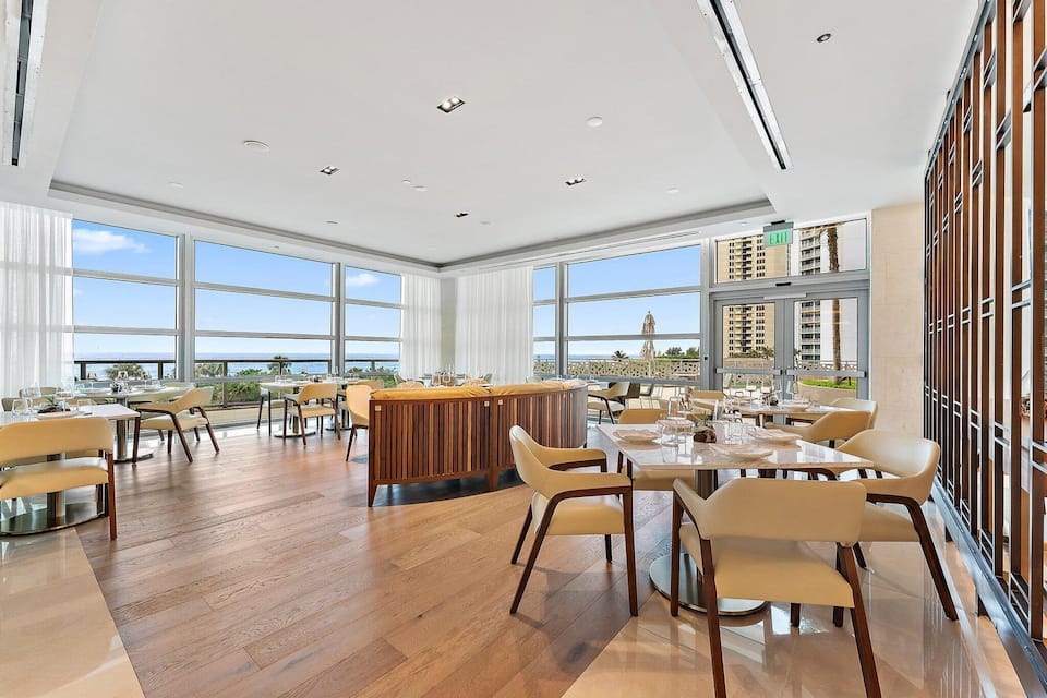A resort restaurant dining room with ocean views through floor-to-ceiling glass