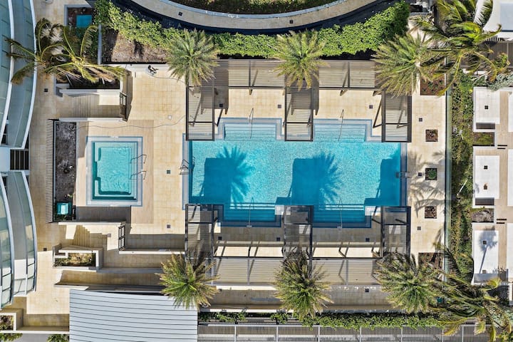 Aerial view of the resort's rooftop pools and cabanas among palms
