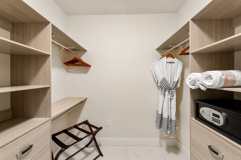 The fitted walk-in closet with robes, a luggage rack and an in-room safe