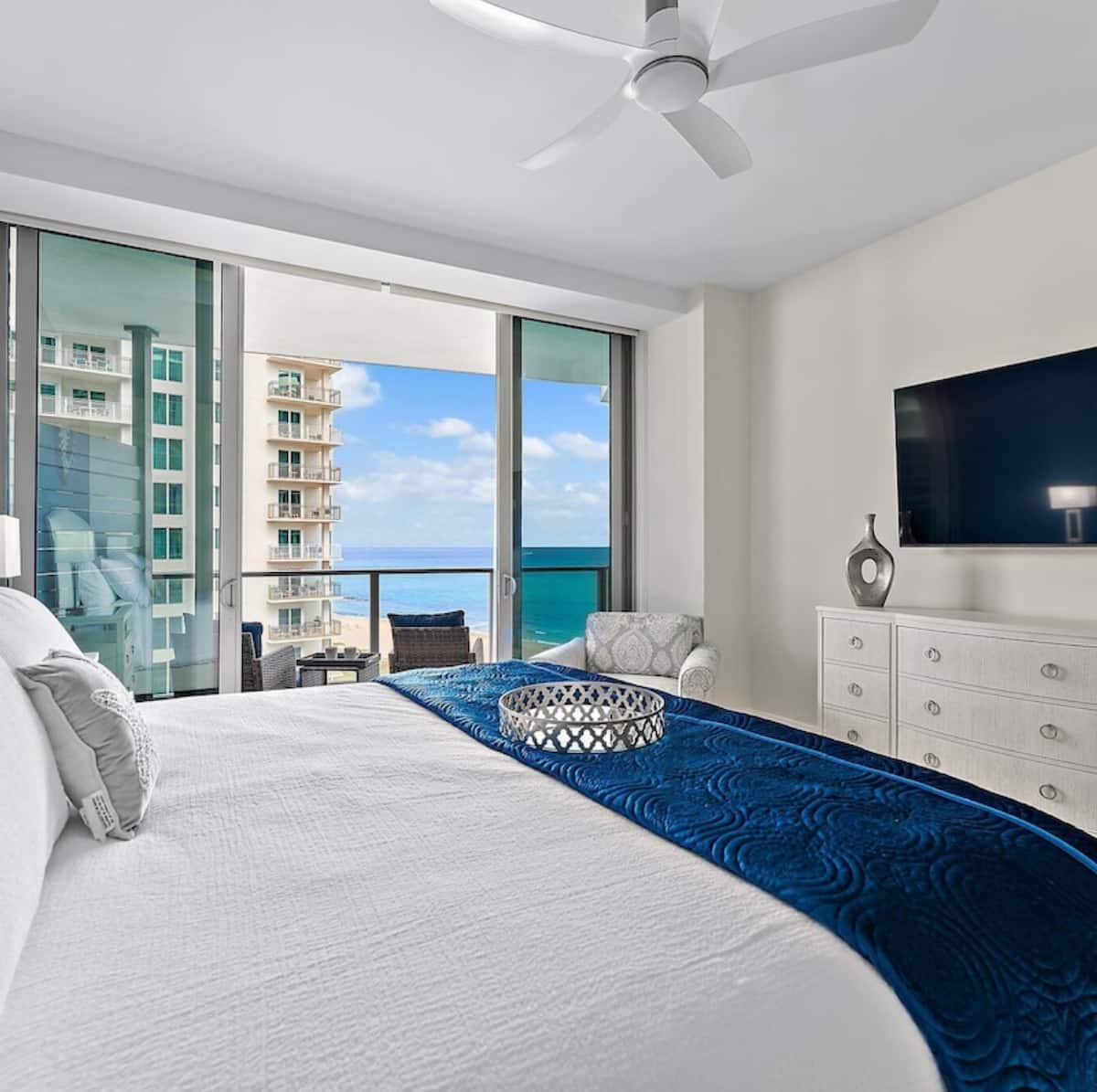 King suite with premium linens, the balcony and the ocean visible through floor-to-ceiling glass