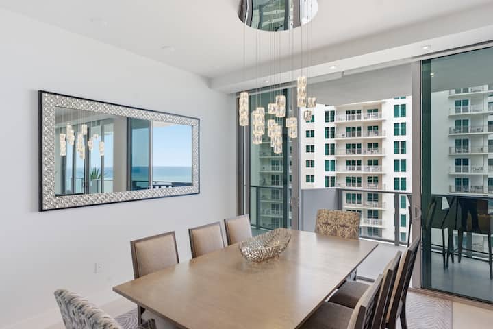 The dining table for eight beside the mirrored wall, with the neighbouring tower through the glass