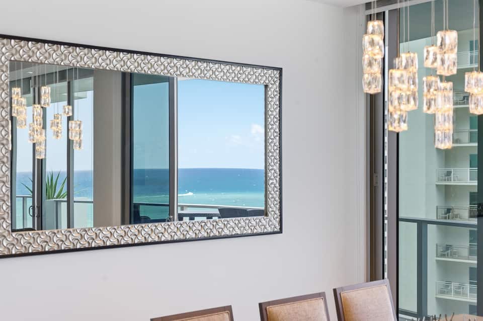 The dining room with its crystal chandelier and mirror, the balcony doors open to the ocean