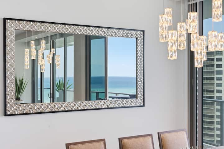The mirrored wall beside the dining table reflecting the ocean view
