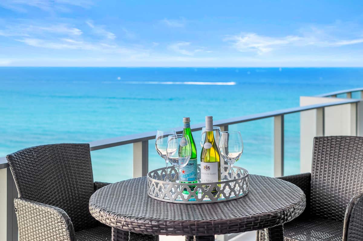 A balcony table set with wine and glasses, the Atlantic filling the view behind