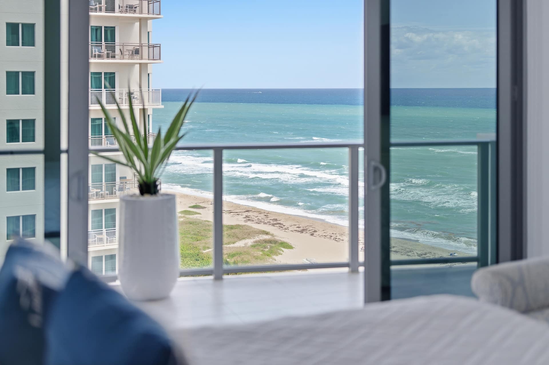 A bedroom corner opening to the balcony, with the ocean stretching to the horizon