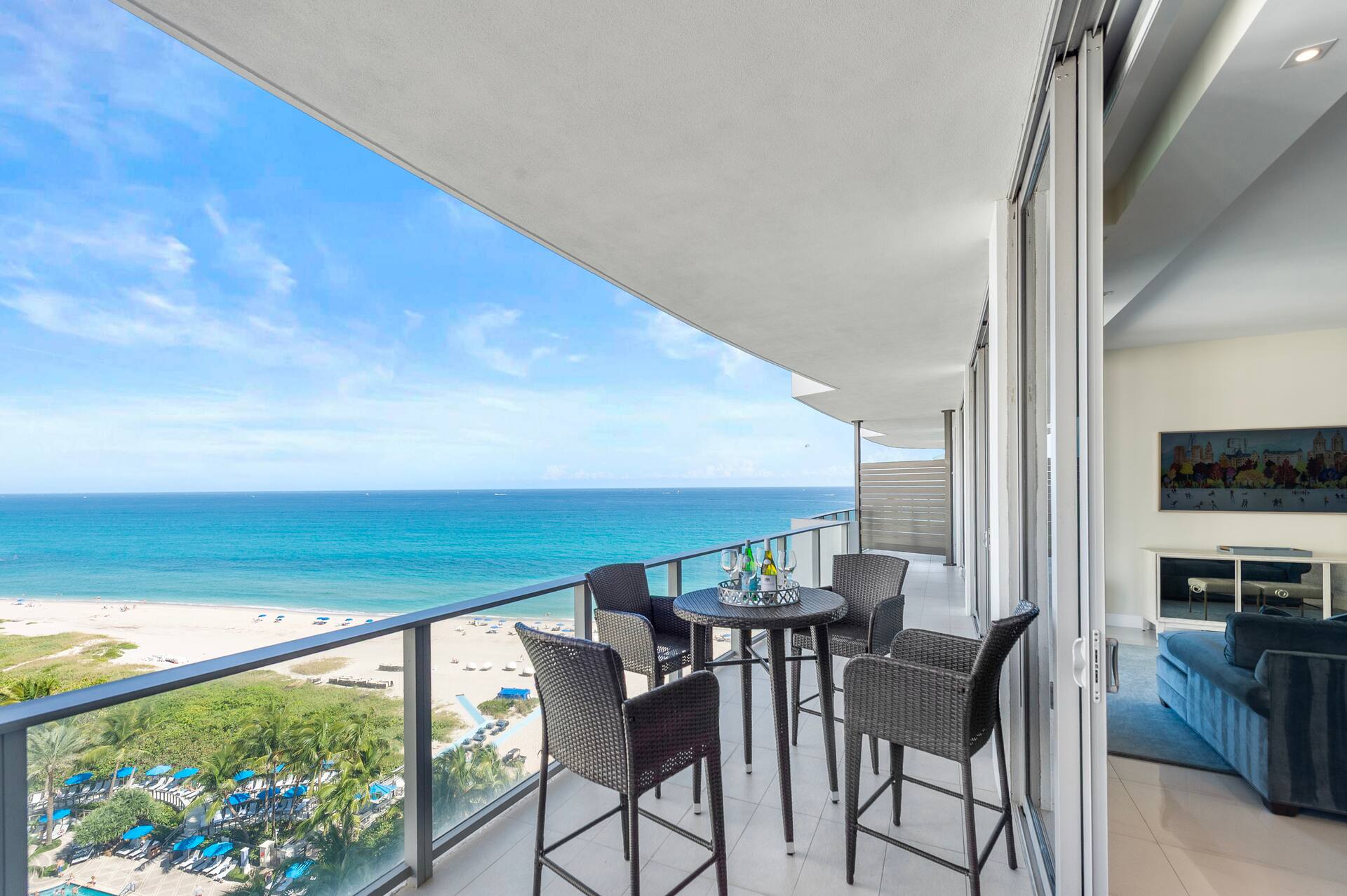 The long curved balcony with wicker lounge chairs, overlooking the beach and turquoise water