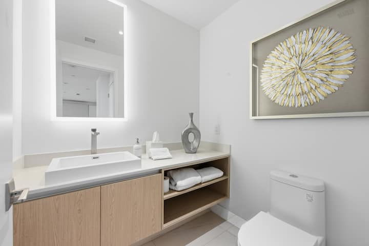 The powder room with a floating vanity and a sunburst artwork